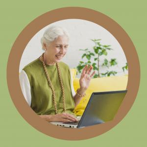 Uśmiechnięta starsza kobieta siedzi przed laptopem