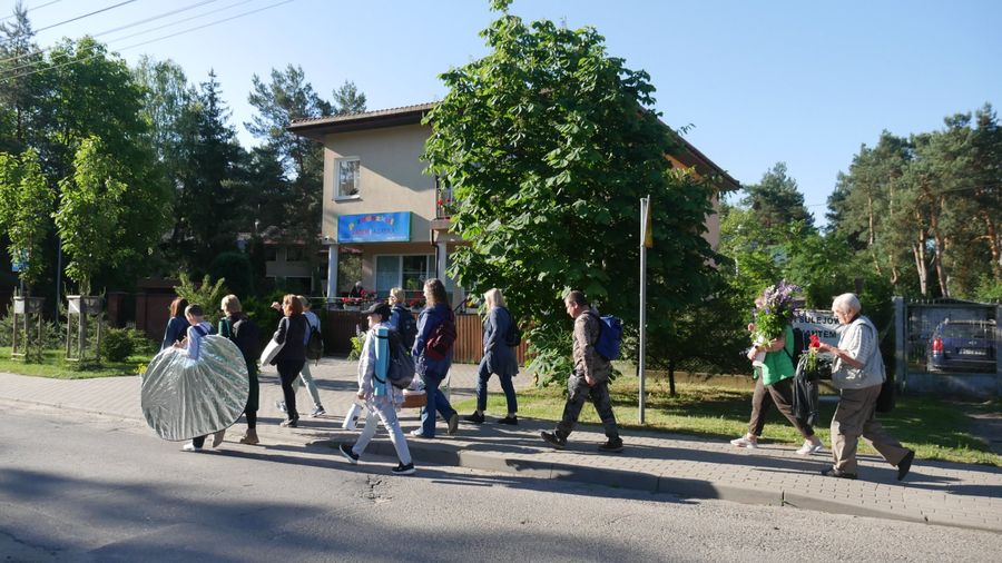 Uczestniczy warsztatów idą na plener, niosą sprzęt i kwiaty.
