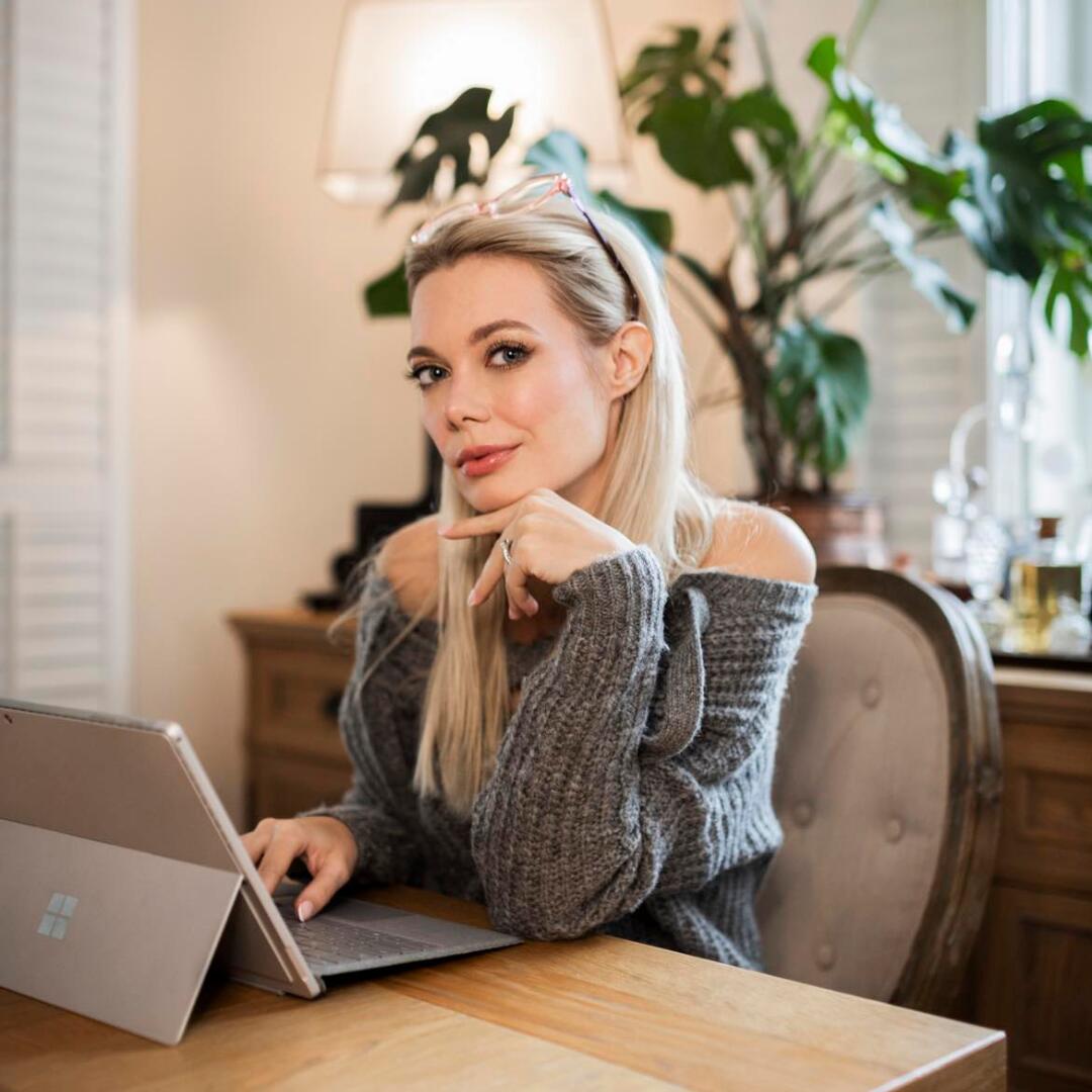 zdjęcie kobiety siedzącej przy laptopie w pomieszczeniu biurowym, w tle rośliny